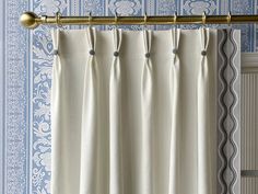 the curtain is hanging in front of a window with blue and white wall paper behind it