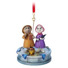 an ornament with two people holding a bell