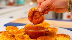 a person dipping sauce onto some food on a plate