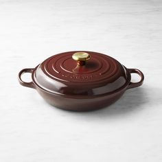 a brown casserole dish with a golden lid on a marble countertop top