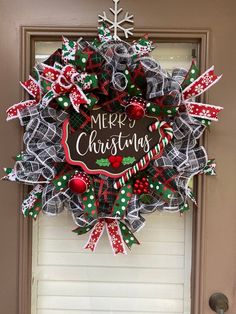 a christmas wreath on the front door with merry written on it and red, white and green decorations