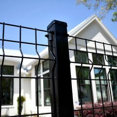 a house behind a black fence with a white house in the background