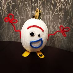 a white pumpkin with red and blue painted on it's face is sitting on a table