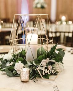 the centerpieces on this table are made out of metal, with greenery and candles