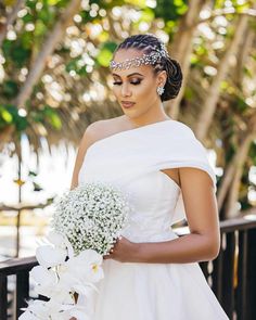 a woman in a white dress holding a bouquet of flowers and wearing a tiara