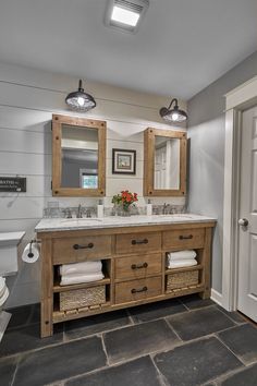 a bathroom with two sinks, mirrors and lights on the wall next to a toilet