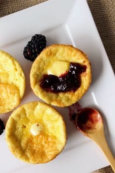 three small pastries on a white plate with berries