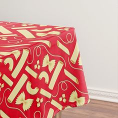 a red table cloth with yellow and white designs on it in front of a wooden floor