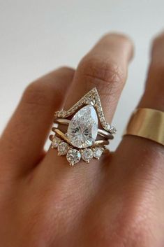 a woman's hand with two rings and an engagement ring on top of her finger