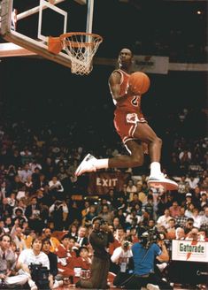 a basketball player jumping up into the air to dunk a ball in front of an audience