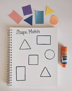 a notebook with shapes drawn on it next to crayon markers and a marker