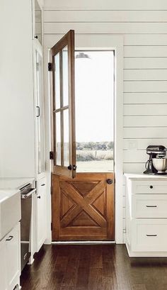 a wooden door is open in a white room with wood flooring and cabinetry