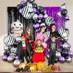 a group of people in halloween costumes posing for a photo with balloons and decorations behind them