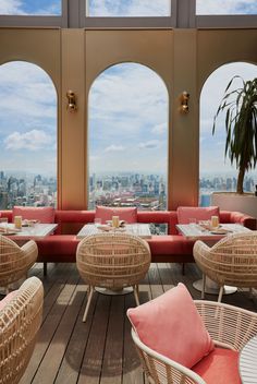 an outdoor seating area with wicker furniture and large round windows overlooking the cityscape