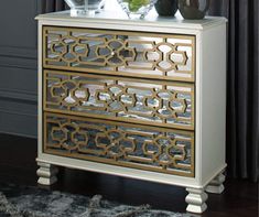 a white and gold dresser with two vases on top