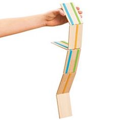 a hand is holding a wooden block with colorful strips on it and the blocks are stacked together