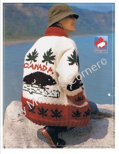 a woman sitting on top of a rock next to the ocean wearing an ugly sweater