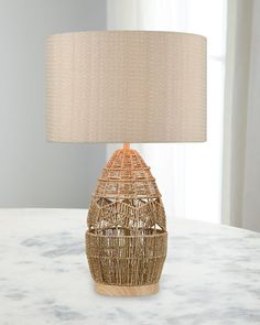 a wicker lamp on a table with a beige shade over the top and bottom