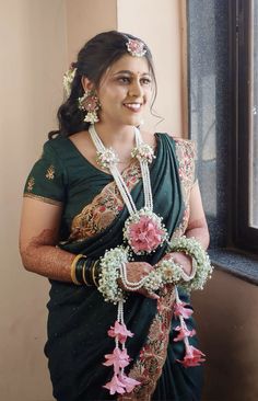 a woman in a green sari holding flowers