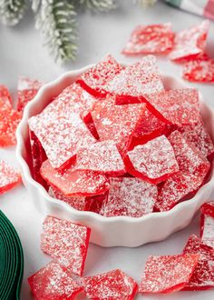 a bowl filled with red sugar cubes on top of a table next to christmas decorations