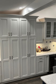 a kitchen with gray cabinets and white counter tops