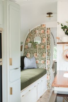 a kitchen with white cabinets and floral wallpaper on the walls, along with a window seat