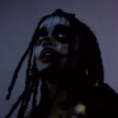 a man with dreadlocks and makeup painted on his face looking to the side