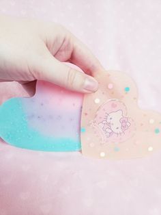 a hand holding a heart shaped brooch on top of a pink blanket with stars