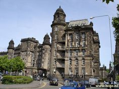 an old building in the middle of a city with cars parked on the street below it