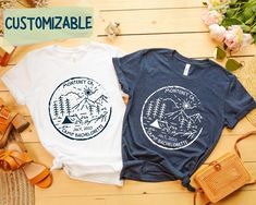 two t - shirts sitting next to each other on top of a wooden table with flowers