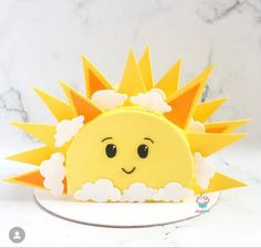 a cake shaped like a sun sitting on top of a white plate with clouds around it