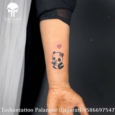 a small panda bear tattoo on the left inner arm and wrist with a heart in it