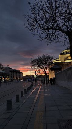 people are walking down the sidewalk at dusk