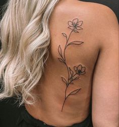 the back of a woman's shoulder with a flower tattoo on her left side