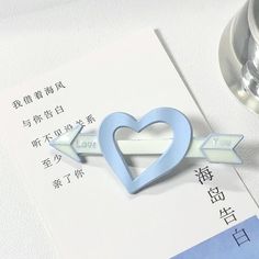 a blue heart shaped brooch sitting on top of a piece of paper