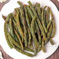 cooked green beans on a white plate with seasoning sprinkles next to it