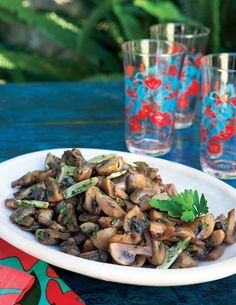 a white plate topped with mushrooms next to two glasses