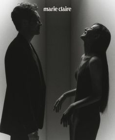 a man and woman standing next to each other in front of a wall with the words marie claire on it