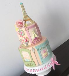 a multi - tiered cake with the eiffel tower on top is decorated in pastel colors