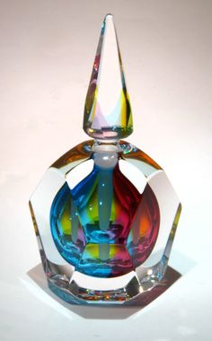 a colorful glass vase sitting on top of a white table next to a bottle opener