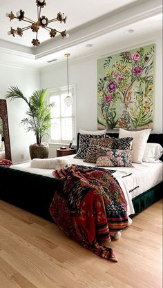 a bedroom with white walls and wooden floors has a large bed covered in colorful blankets