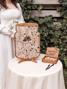 a woman in white dress standing next to a table with an ornate wooden plaque on it