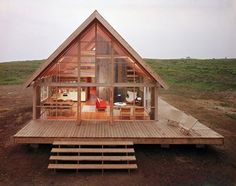 a small wooden house sitting in the middle of a field with stairs leading up to it