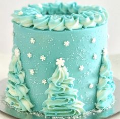 a blue frosted cake decorated with snowflakes and trees