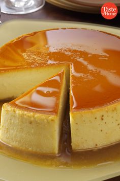 a cheesecake covered in caramel sauce on a plate with one slice cut out