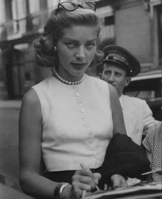 an old black and white photo of a woman signing something in her hand while standing next to a man