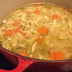 a pot filled with chicken and carrots on top of a stove