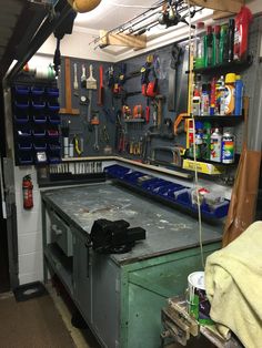 a workbench with tools hanging on the wall and various other items in it