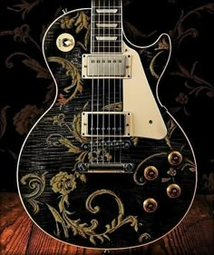 an electric guitar sitting on top of a wooden table next to a black and gold wallpaper