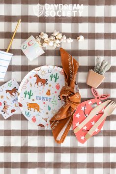 a plaid table cloth with paper plates and utensils on it, along with other items